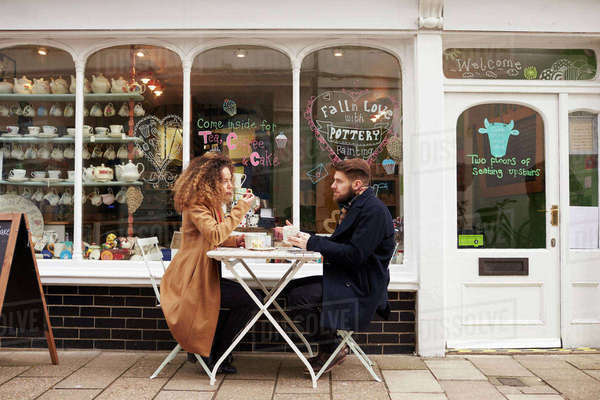 Couple sitting outside cafe enjoying coffee and snack - Stock Photo