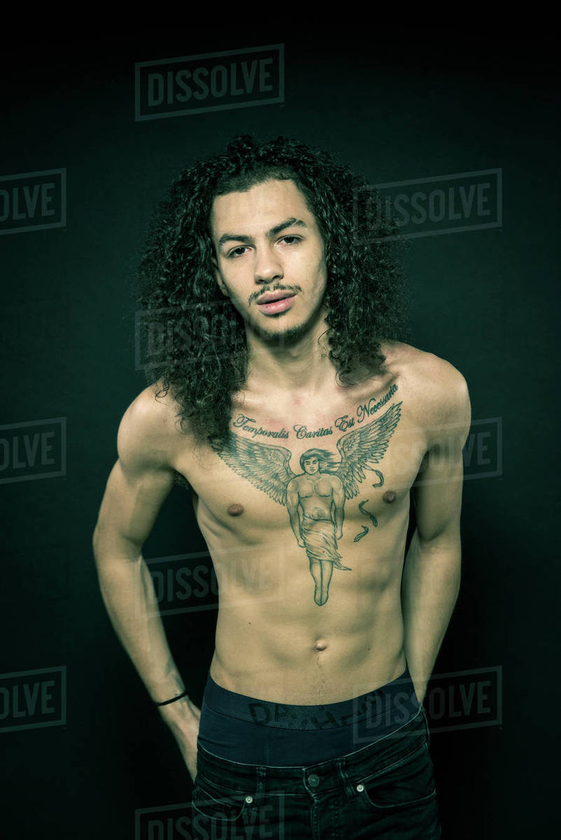 Studio Portrait Of A Young Man With Tattooed Chest And Long Hair