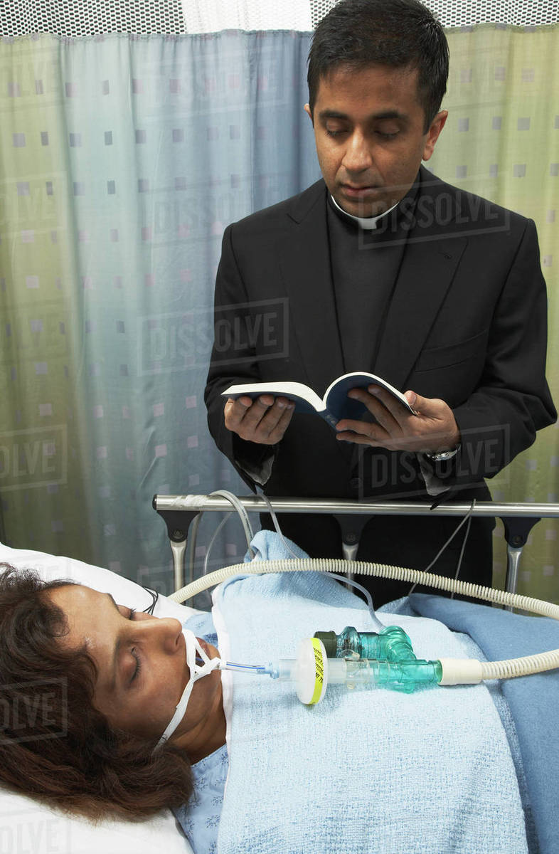 Priest reading last rites to hospital patient Stock Photo Dissolve