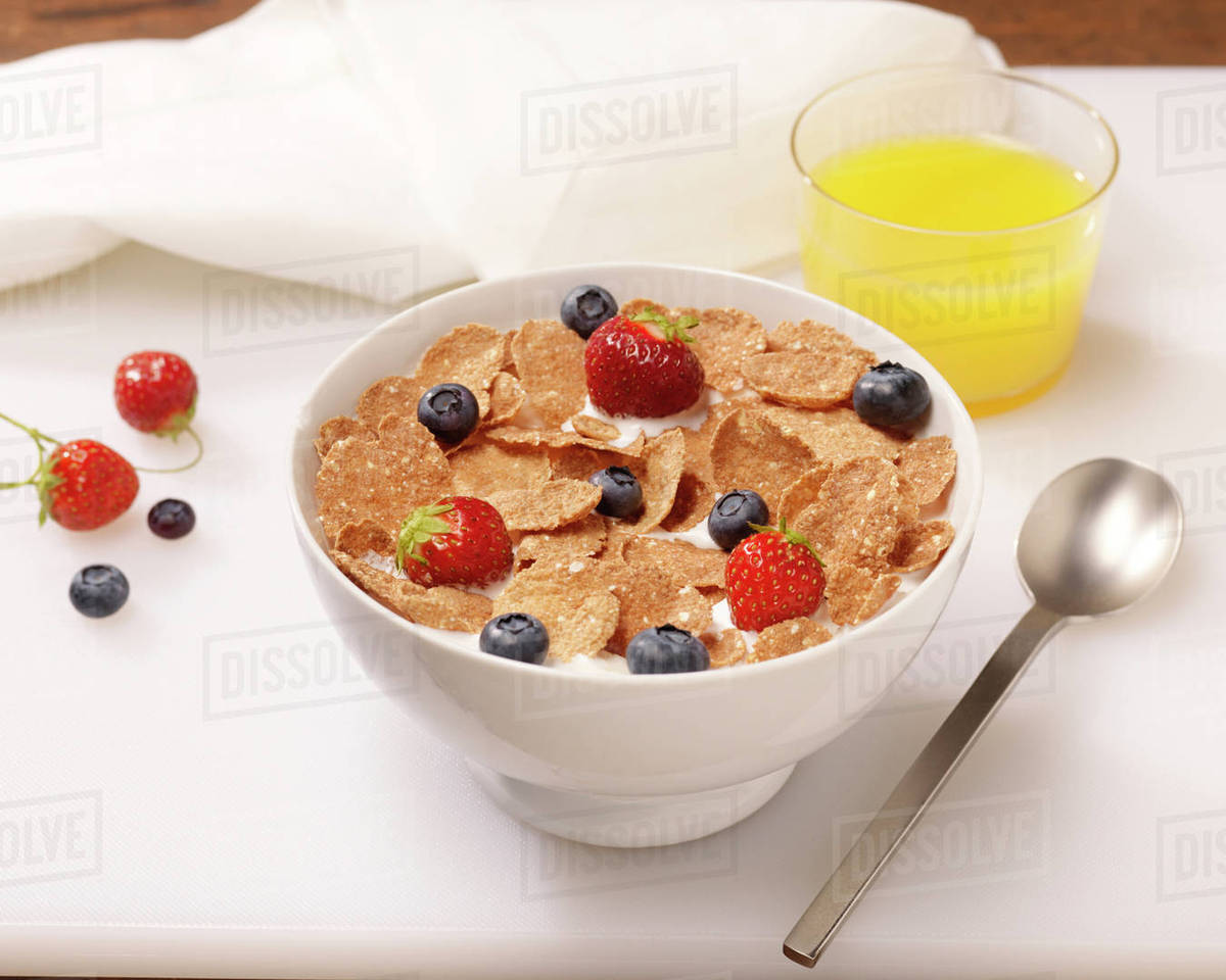 Bowl of Cereal Flakes with Berries and Orange Juice Stock Photo