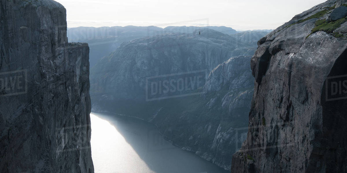 Man walking on slackline between mountains Stock Photo Dissolve
