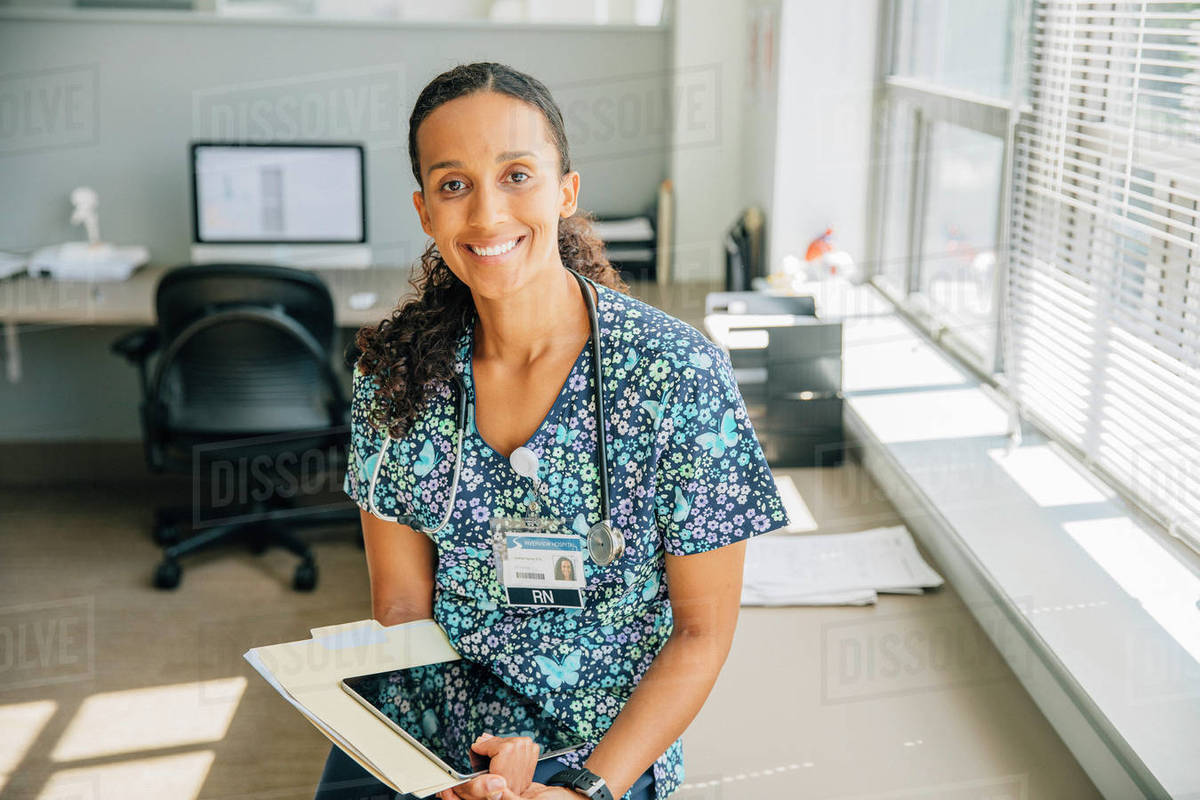 Portrait of smiling nurse holding digital tablet near window Royalty-free stock photo