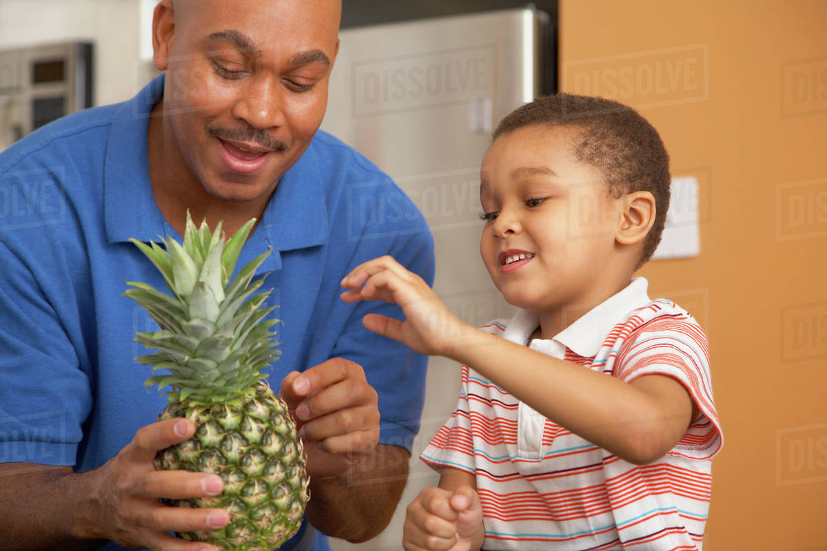 Antiguan father showing pineapple to son Stock Photo Dissolve