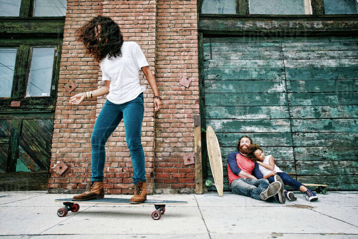 Family riding skateboards on sidewalk Stock Photo Dissolve