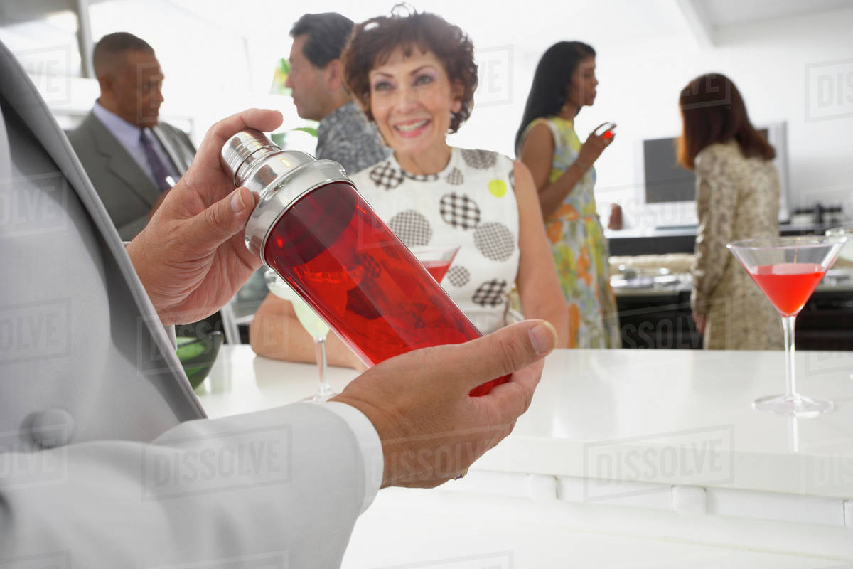 Host mixing martini cocktails at party Stock Photo Dissolve