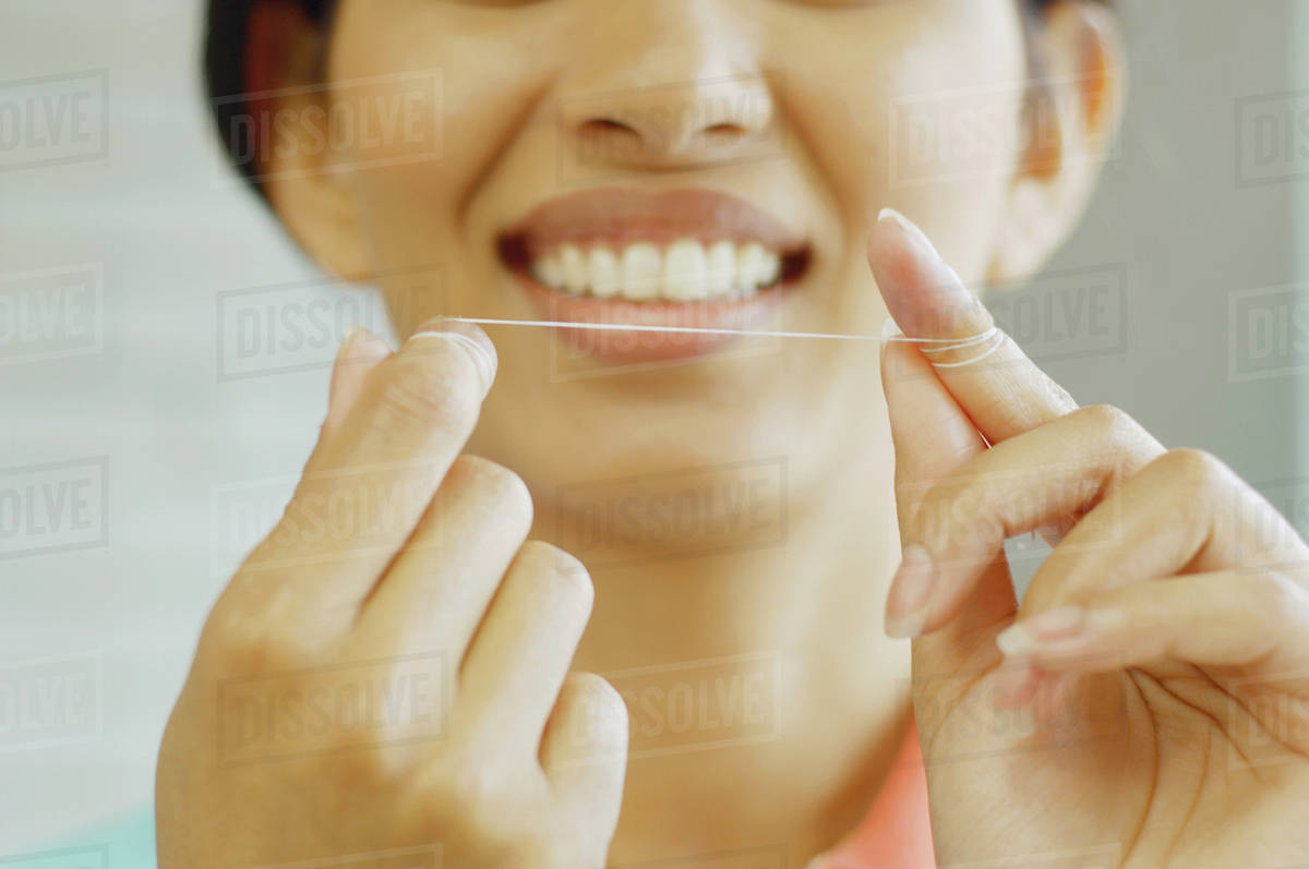 Woman smiling and holding dental floss Stock Photo Dissolve