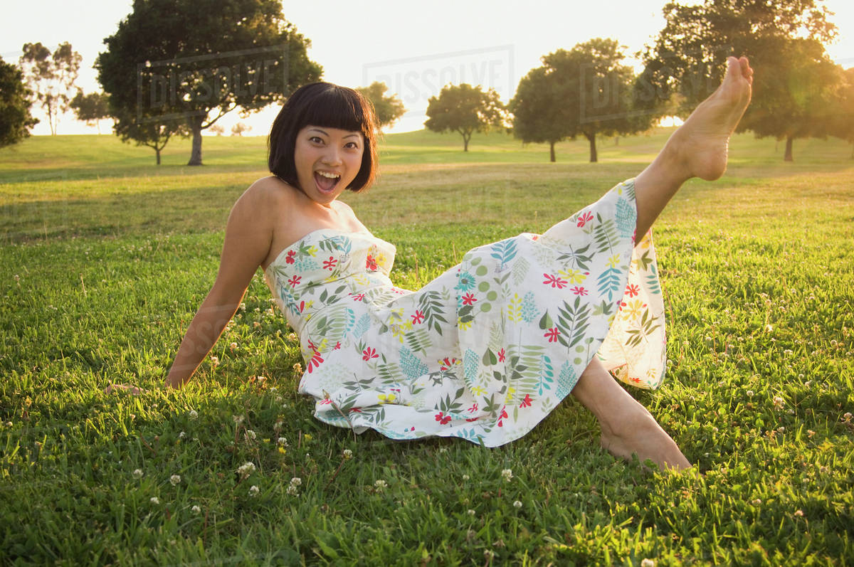 Asian woman kicking up foot in grass Stock Photo Dissolve