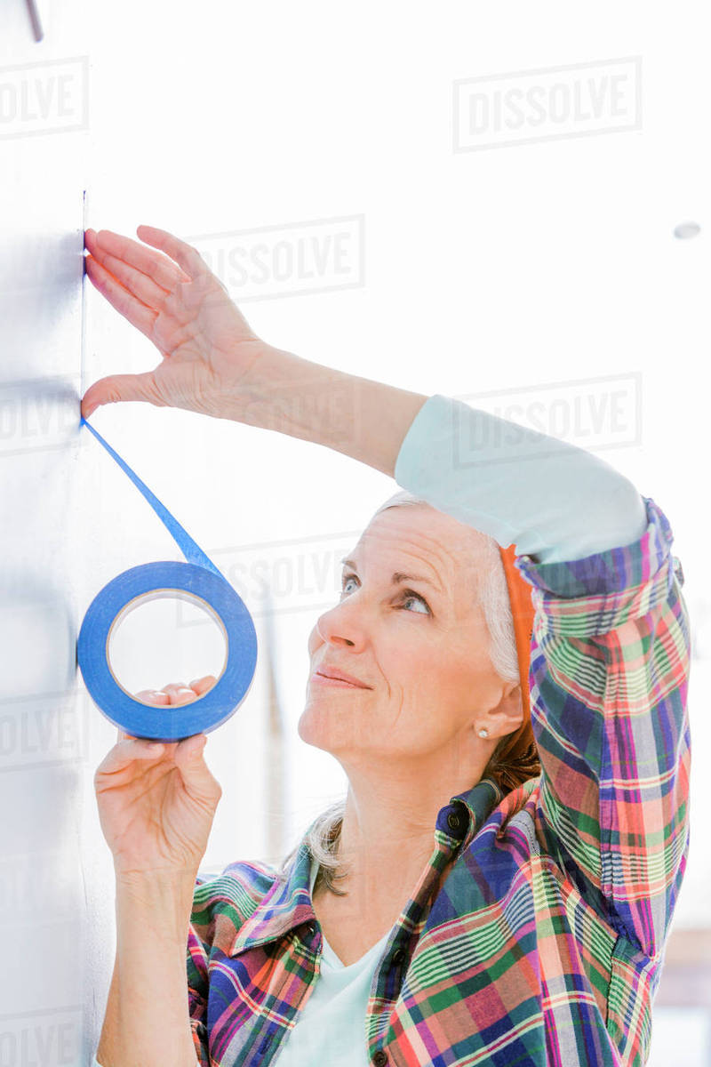 Caucasian woman taping off painting area Stock Photo Dissolve
