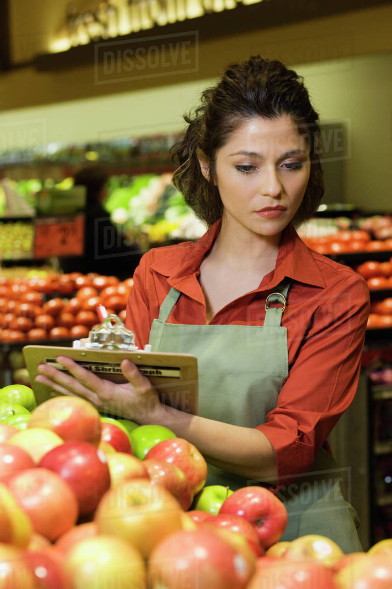 Hispanic woman working in produce section of grocery store Stock