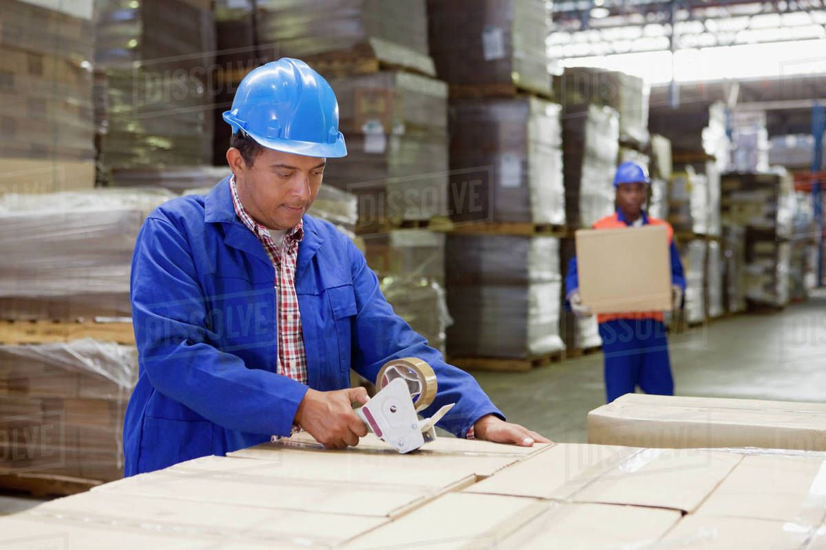 African worker taping boxes in warehouse - Stock Photo - Dissolve