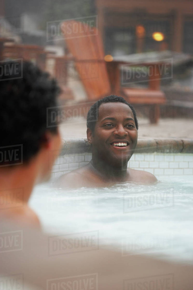 Two multiethnic men sitting in hot tub Stock Photo Dissolve