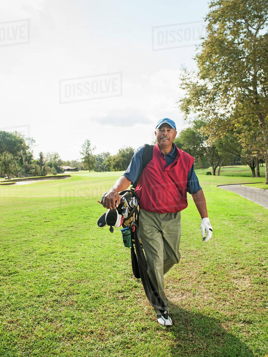 Black man carrying golf clubs Stock Photo Dissolve