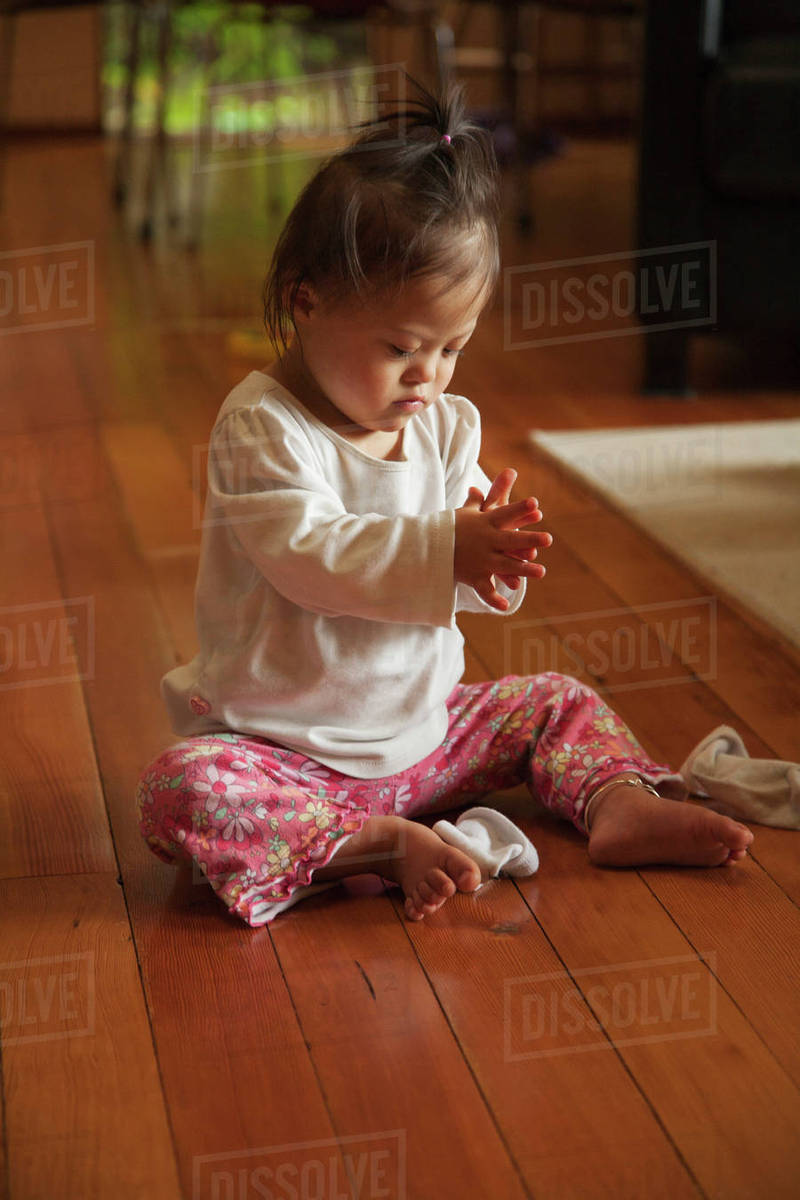 Mixed race baby with Down syndrome playing on floor Stock Photo