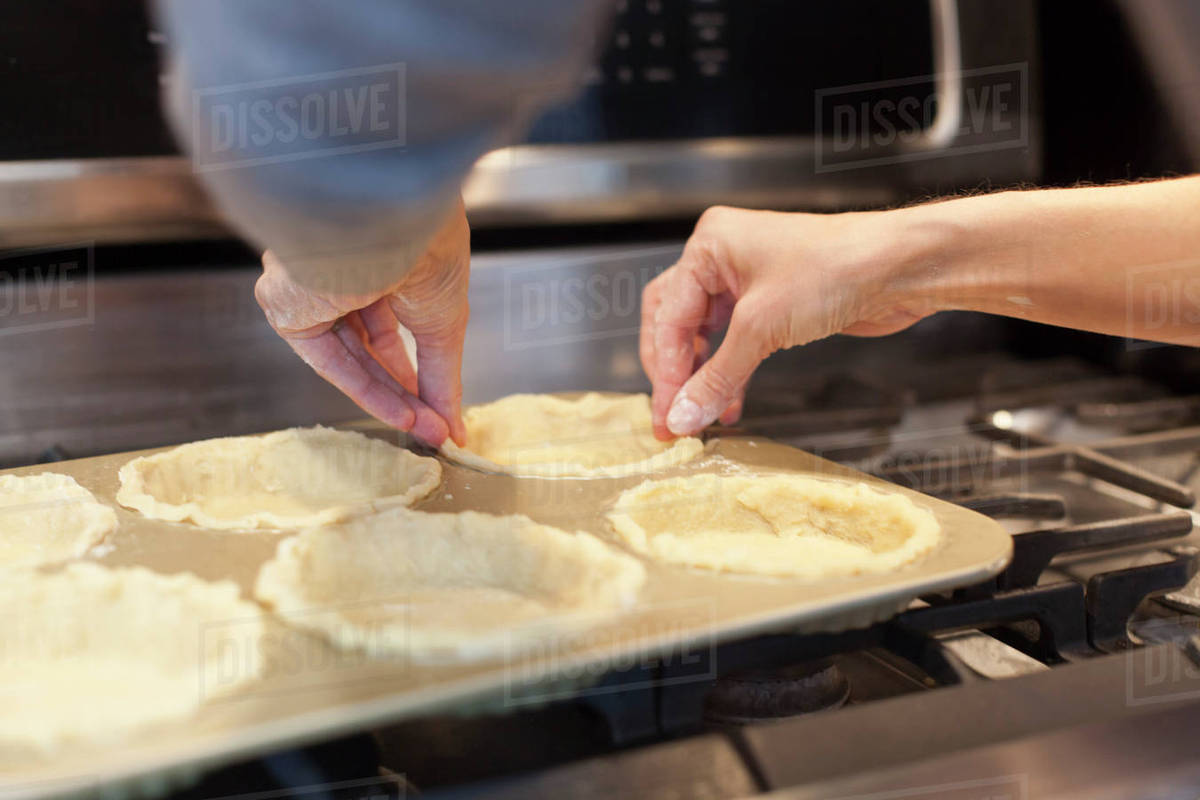 Close up of woman lining pie pans on stove Stock Photo Dissolve