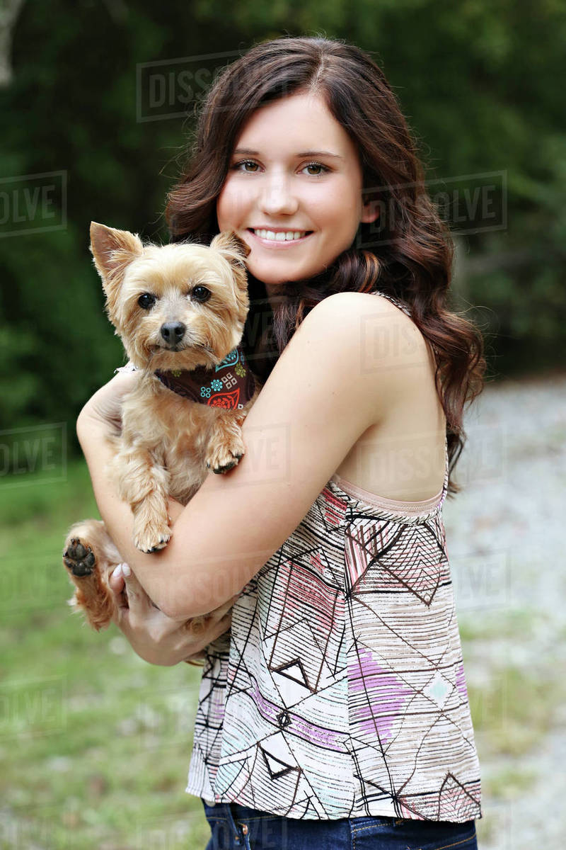 Teenage girl carrying puppy in rural field Stock Photo Dissolve