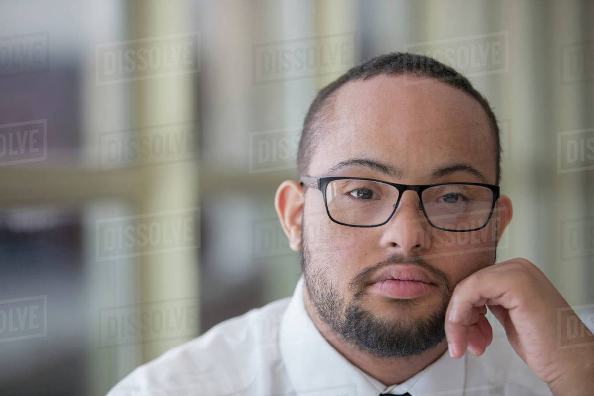 Mixed race man with down syndrome resting chin in hands Stock Photo