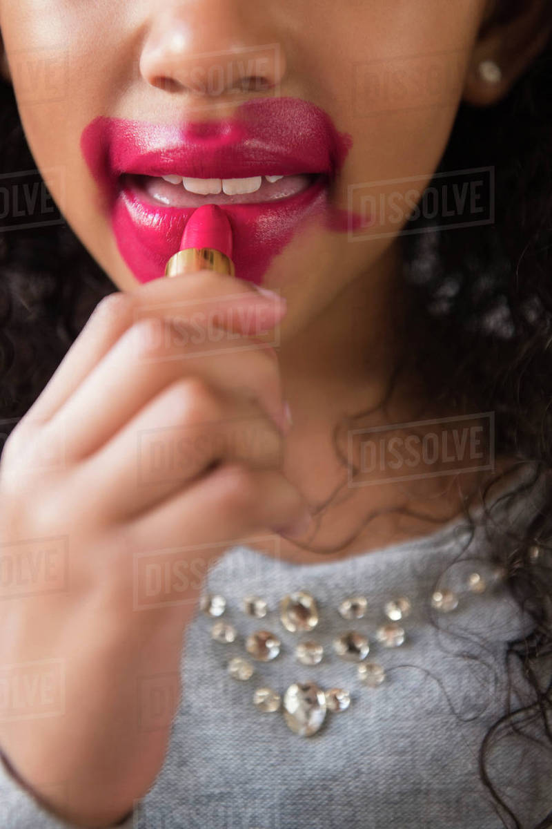 Mixed Race girl applying messy lipstick Stock Photo Dissolve