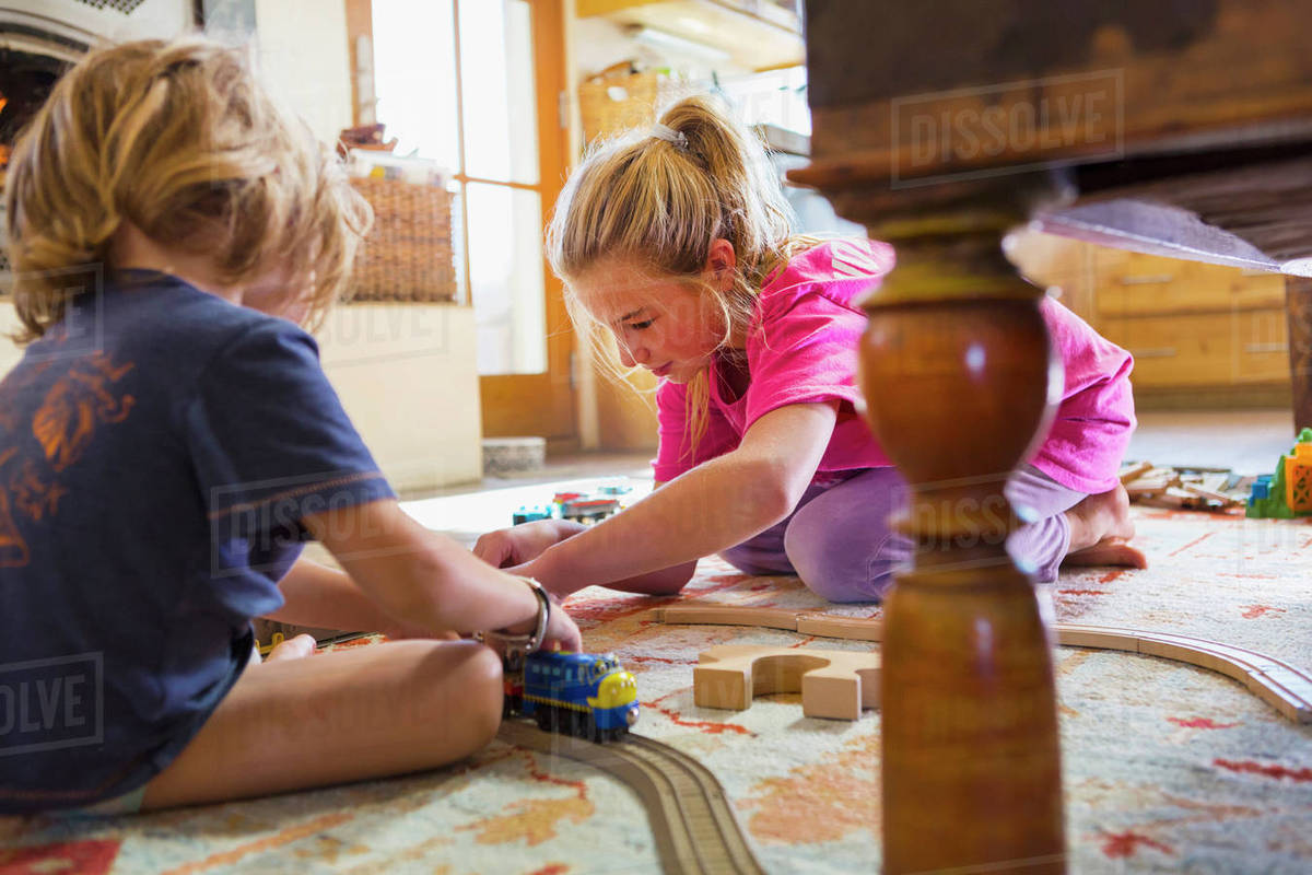 Brother and sister playing with toy race track on floor Stock Photo
