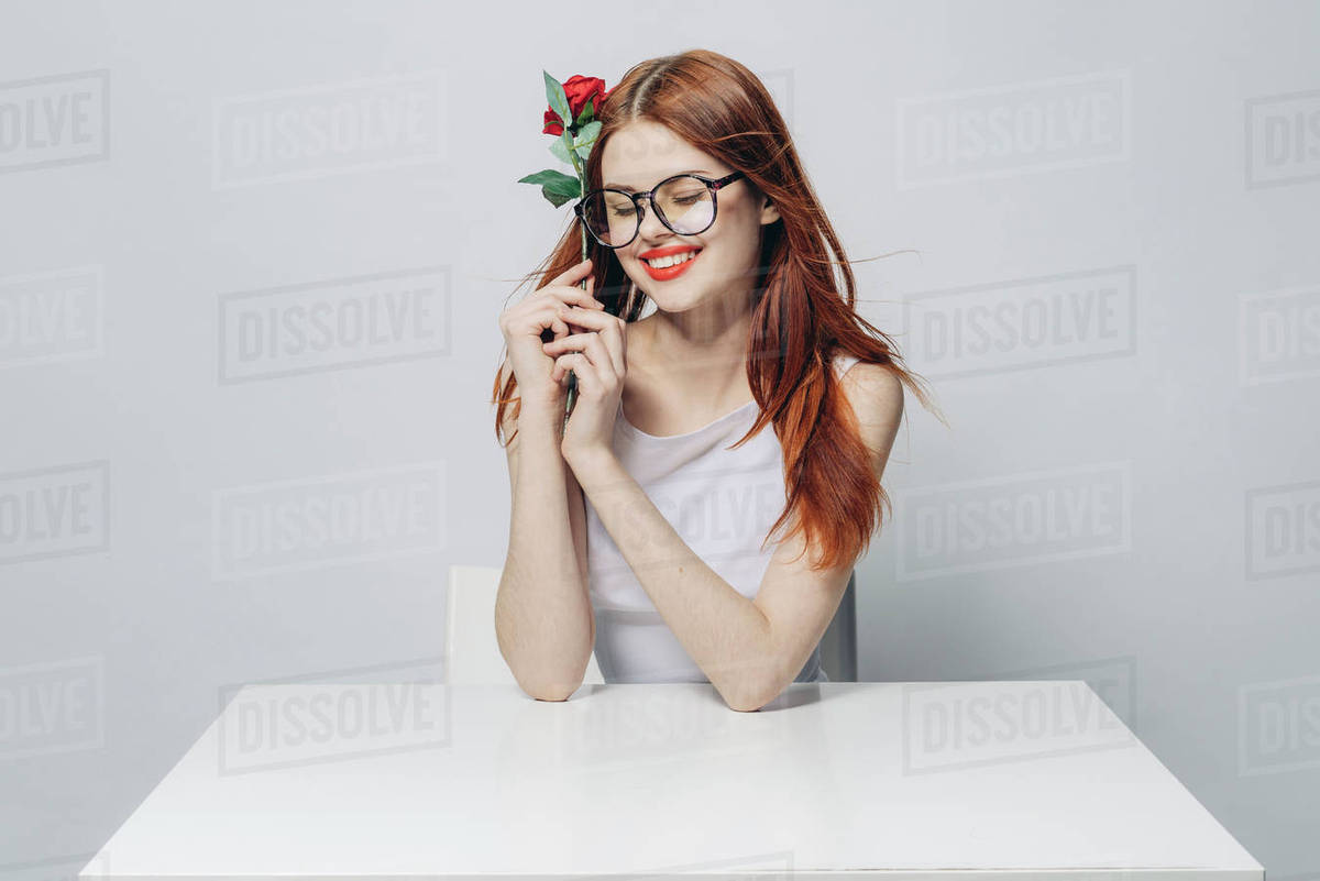 Caucasian woman sitting at windy table holding rose - Royalty-free ...