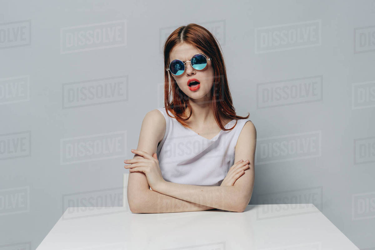 Caucasian woman with attitude sitting at table wearing sunglasses