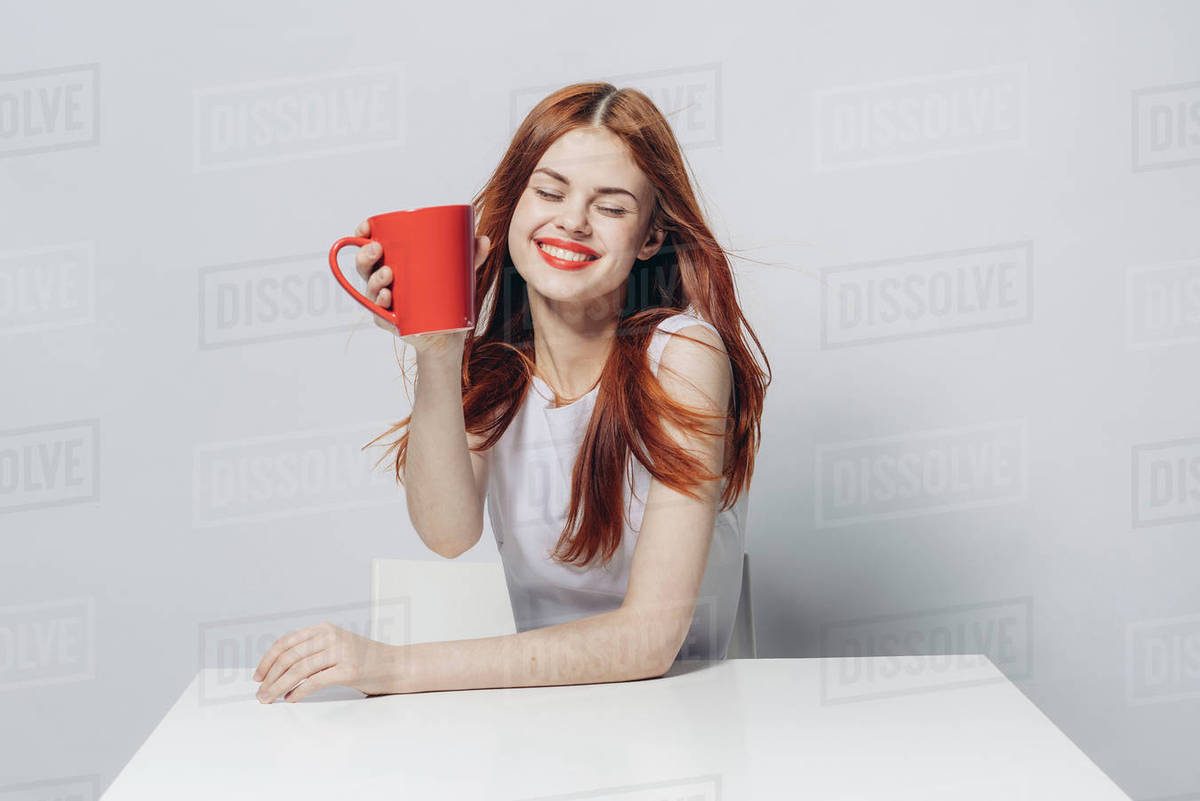Caucasian woman sitting at windy table holding red cup - Royalty-free ...