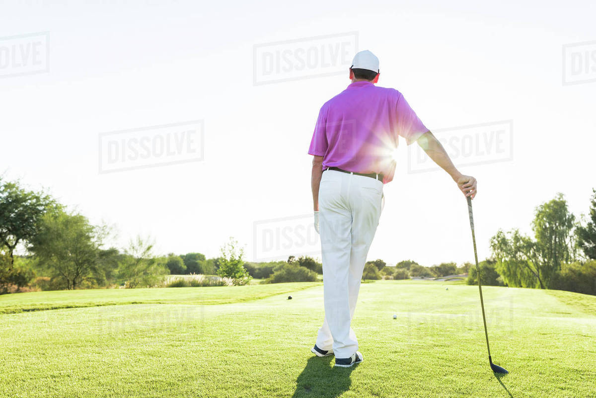 Hispanic golfer leaning on golf club on golf course Stock Photo