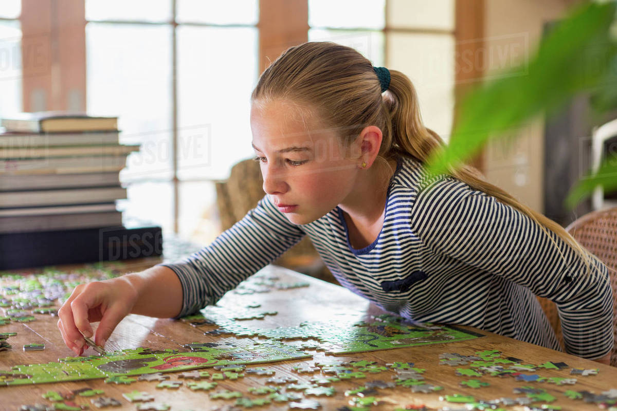 Caucasian girl solving jigsaw puzzle Stock Photo Dissolve