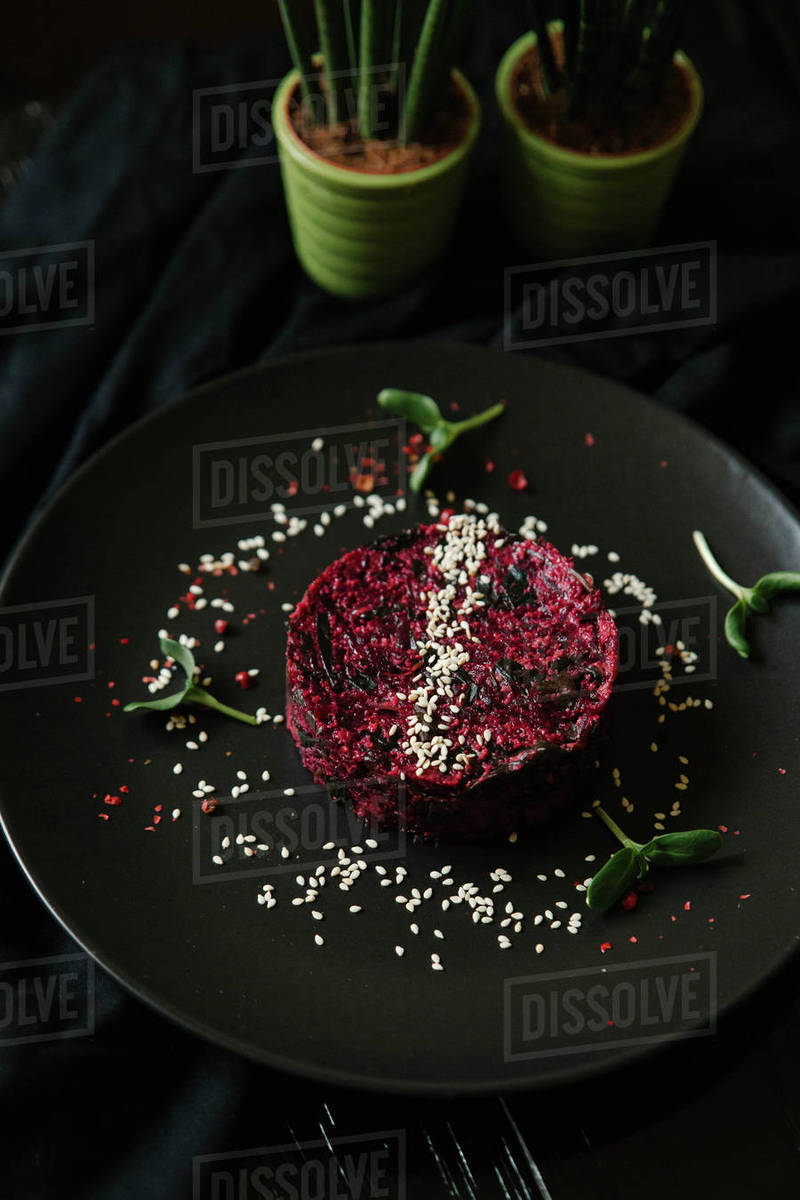 Sesame seeds and garnish on red food on plate Stock Photo Dissolve