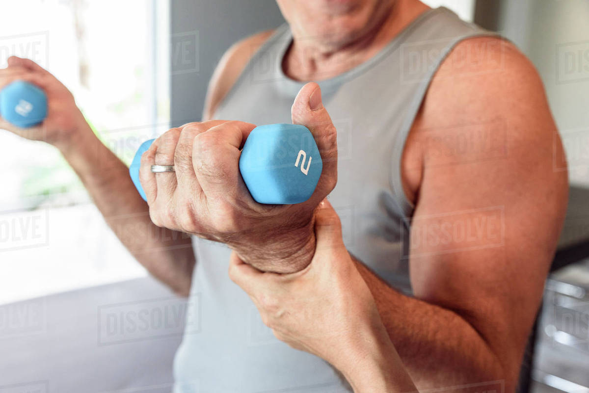 Physical therapist helping man lifting weights Stock Photo Dissolve