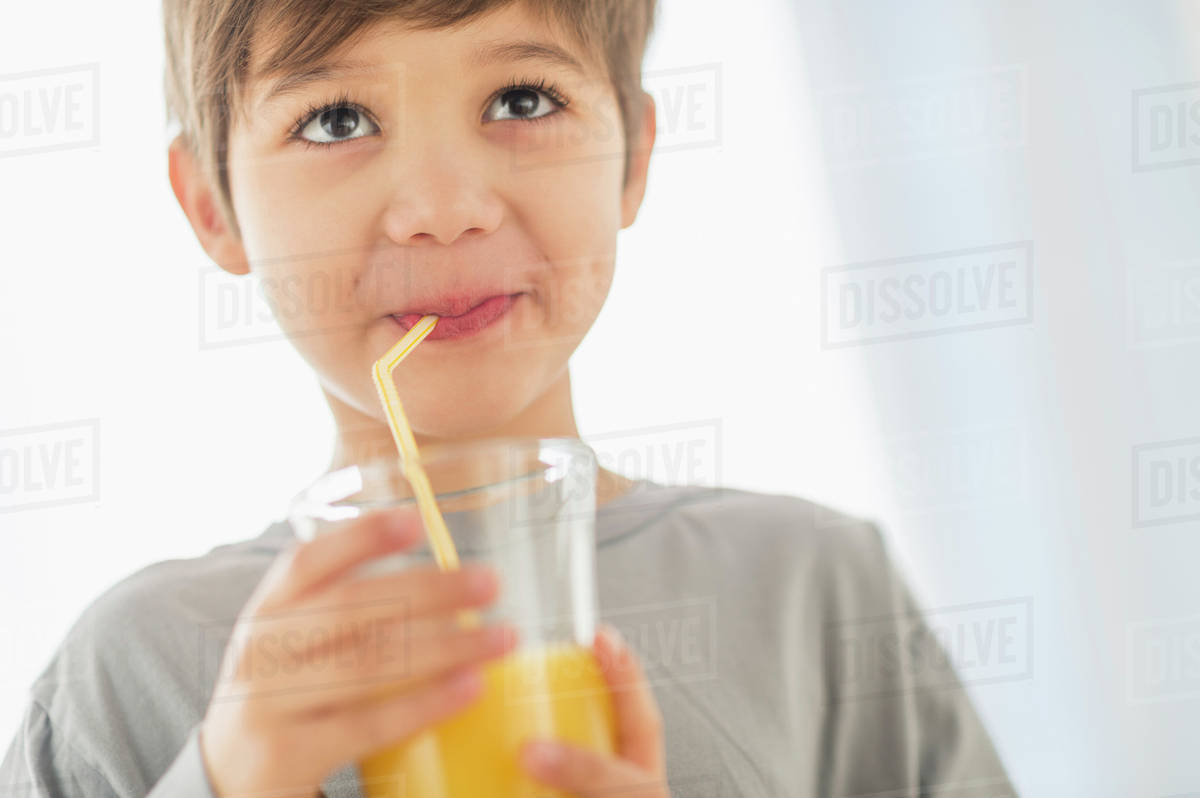 Hispanic boy drinking juice with straw Stock Photo Dissolve
