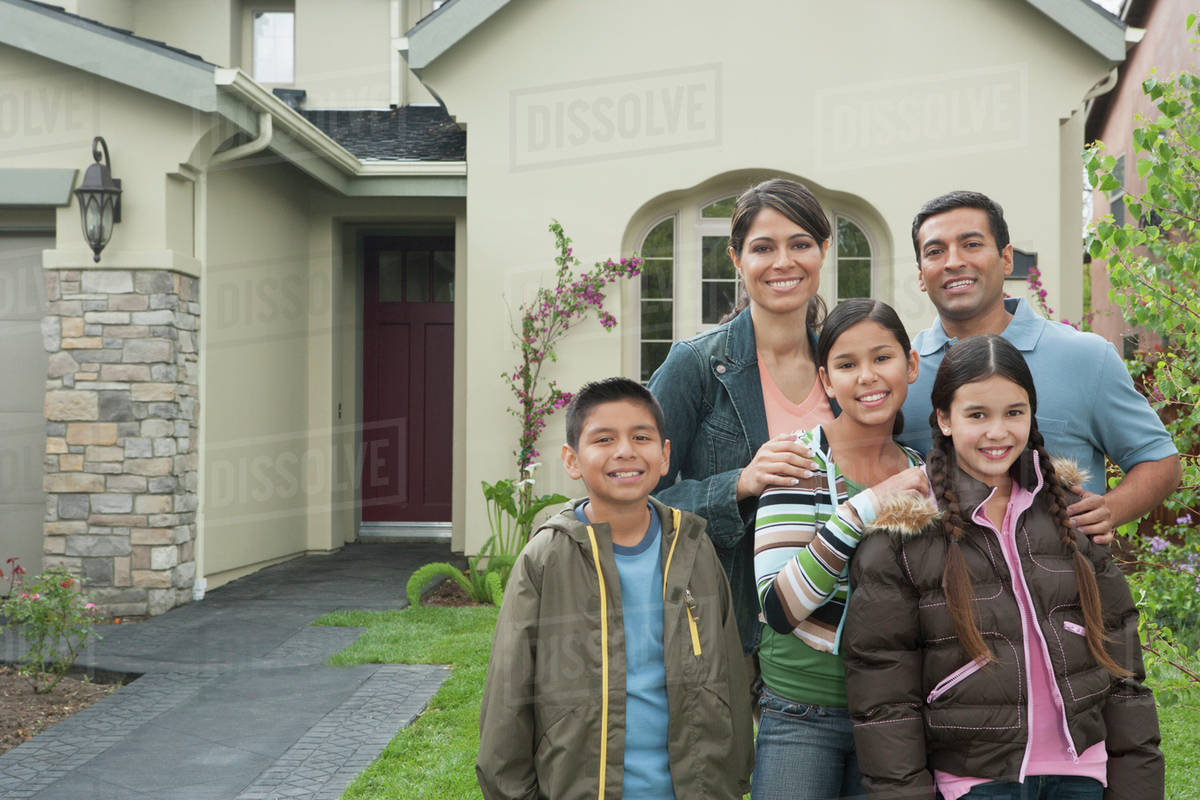Hispanic family smiling outside home Stock Photo Dissolve
