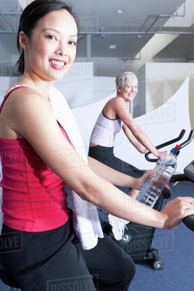 Women using exercise machines in gym Stock Photo Dissolve