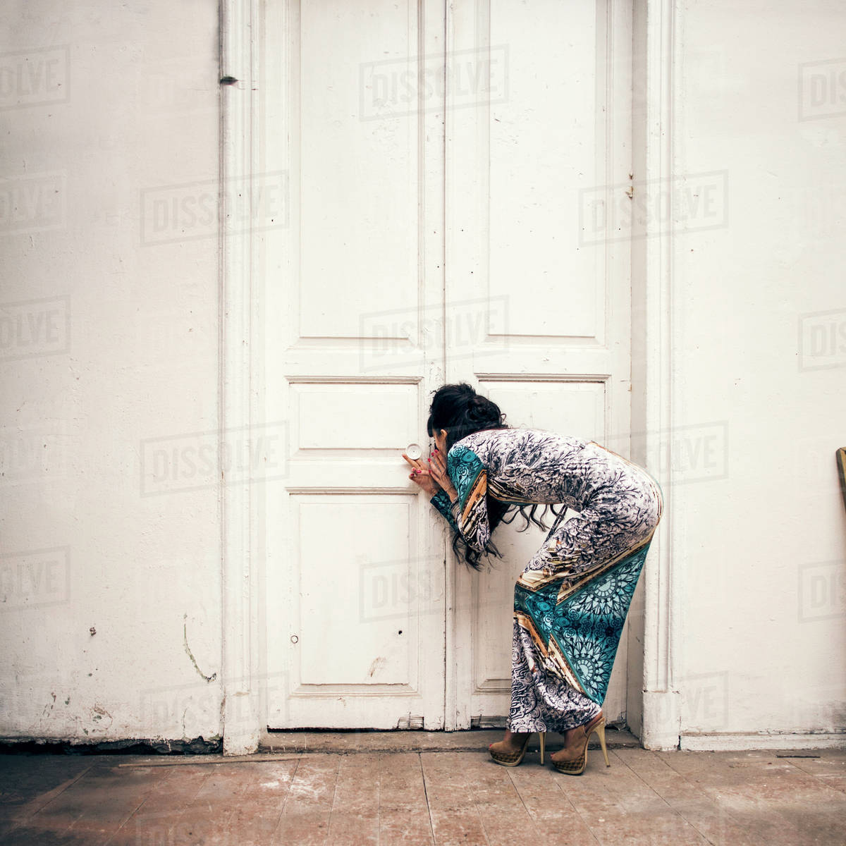 Caucasian woman peering through keyhole - Stock Photo - Dissolve