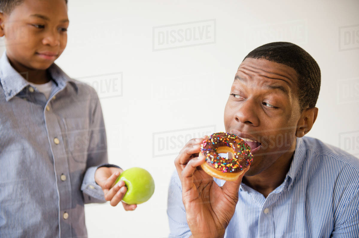 Boy offering father healthy snack Stock Photo Dissolve