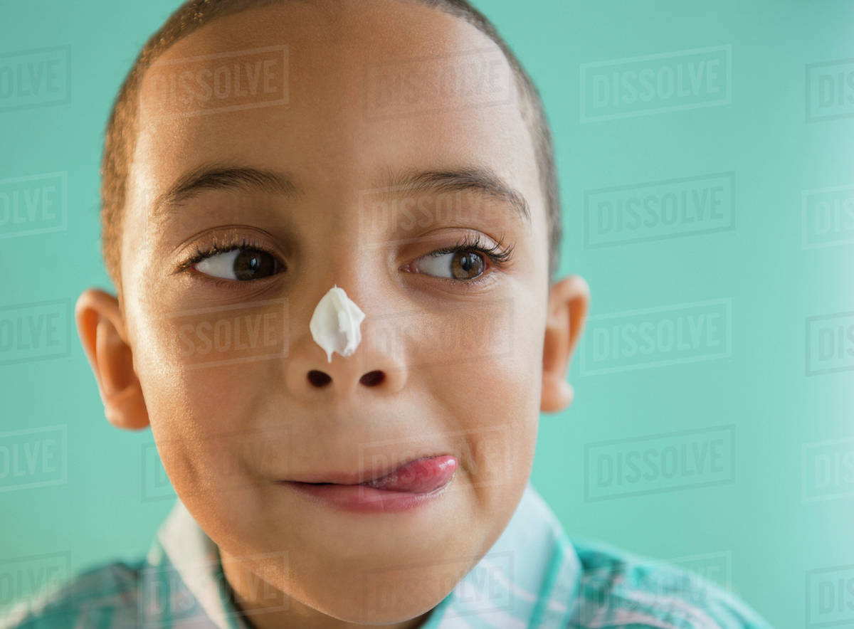 Mixed race boy with icing on nose Stock Photo Dissolve