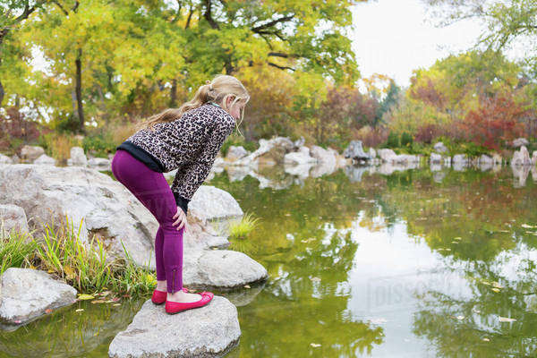 Caucasian girl crouching on rock in pond - Royalty-free Stock Photo ...