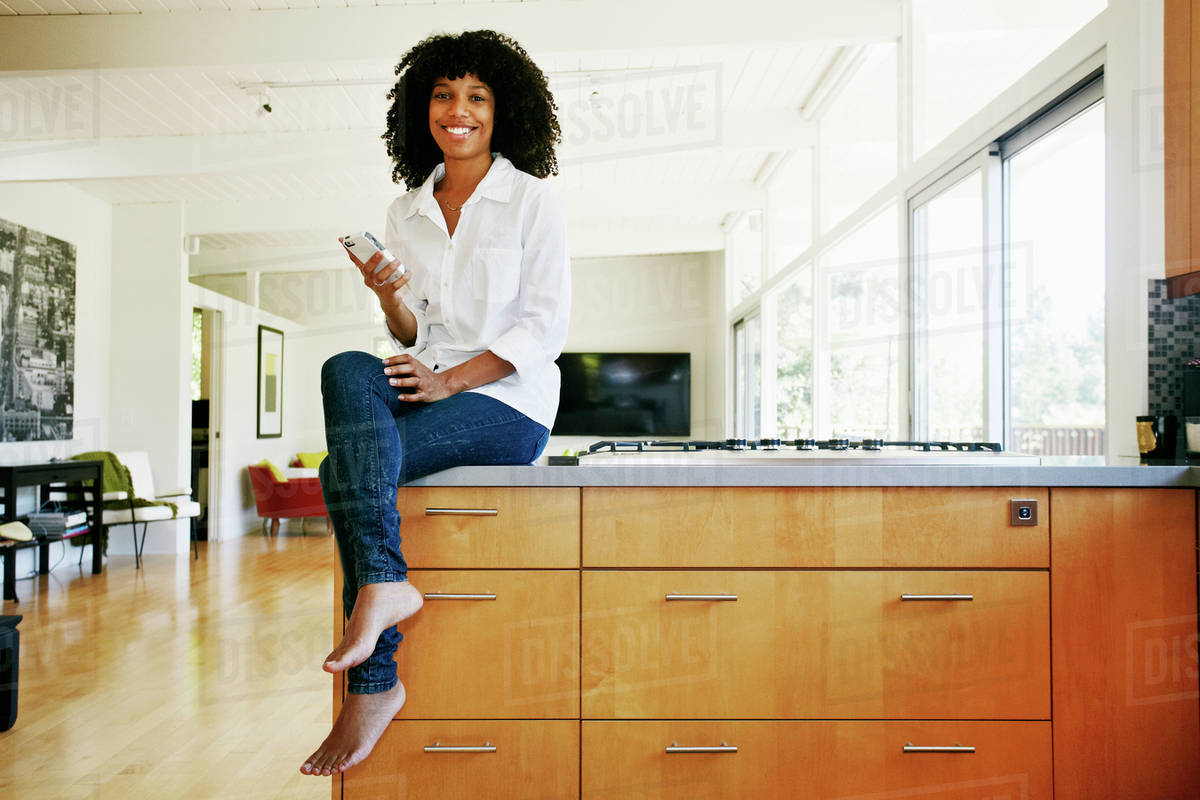 Mixed race woman using cell phone in domestic kitchen Royalty-free stock photo