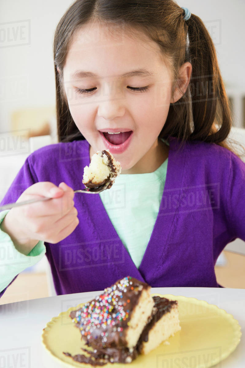 Mixed race girl eating cake Stock Photo Dissolve