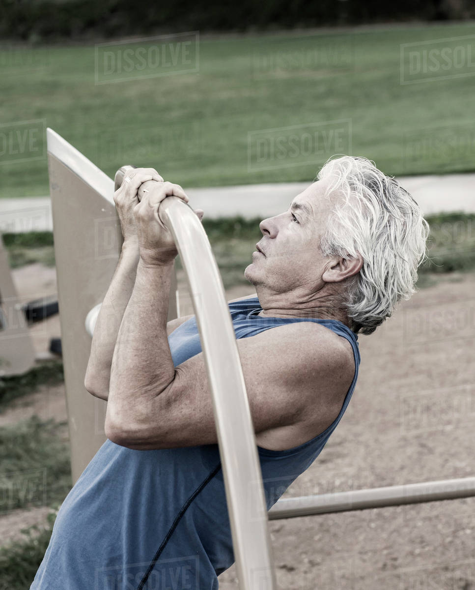 Hispanic man doing pullups in park Stock Photo Dissolve