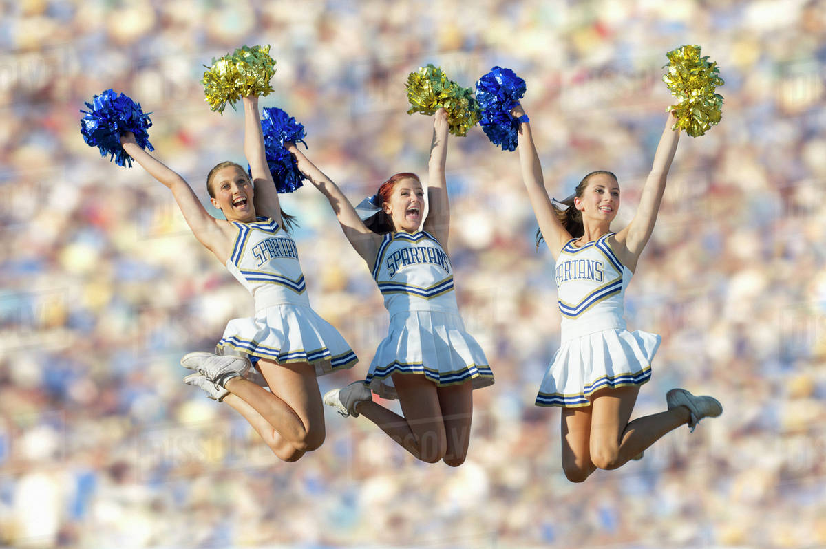 Caucasian cheerleaders jumping in midair Stock Photo Dissolve