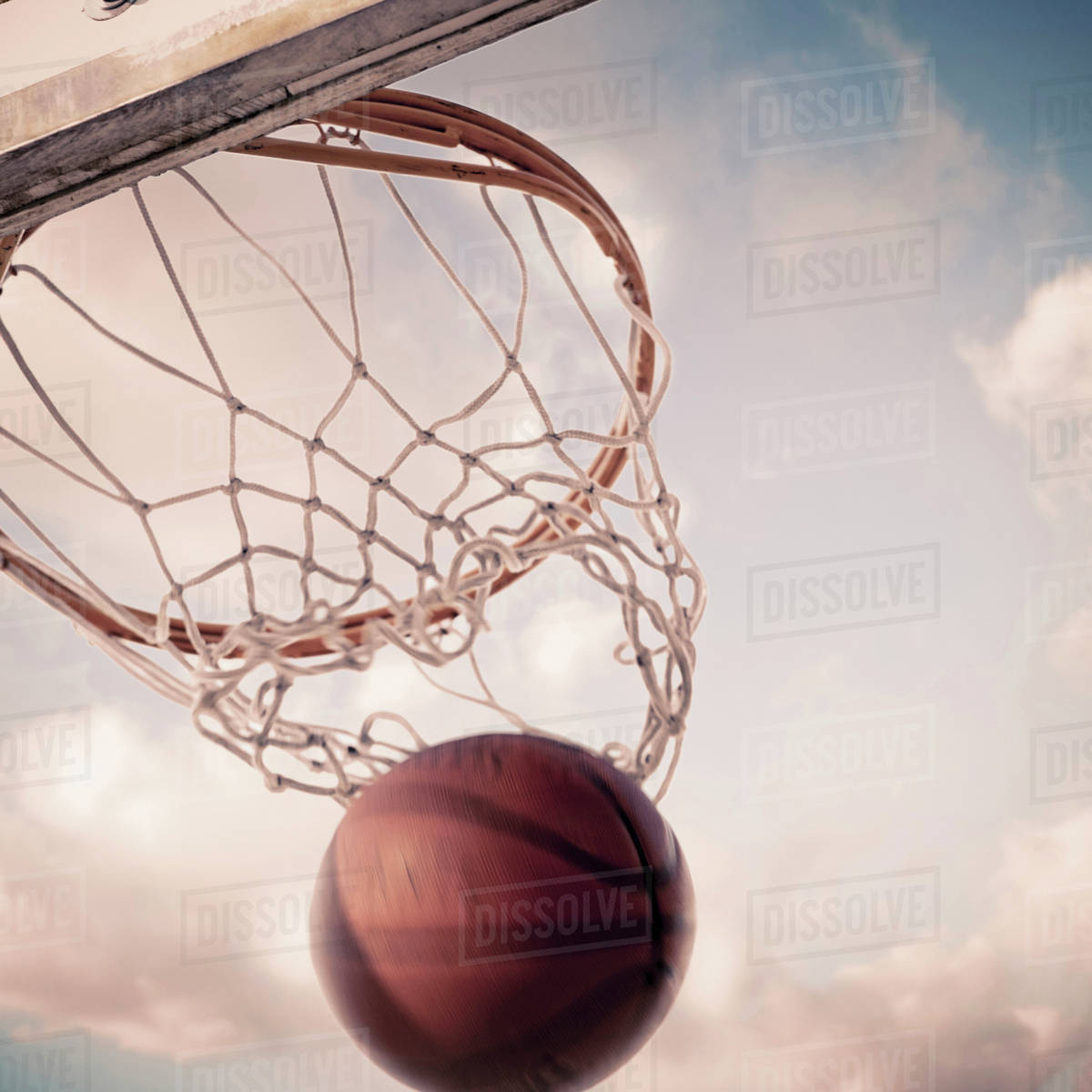 Basketball falling through hoop on court Stock Photo Dissolve