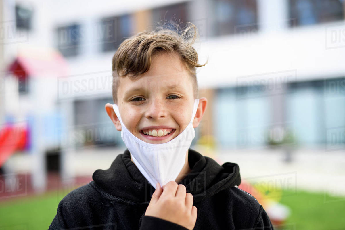 Portrait of happy boy with face mask going back to school after covid
