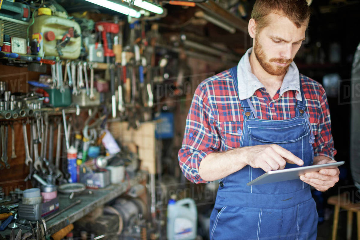 Young man in uniform networking in workshop - Royalty-free Stock Photo ...