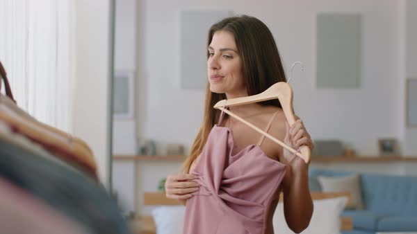 Beautiful young woman getting dressed looking in mirror choosing ...