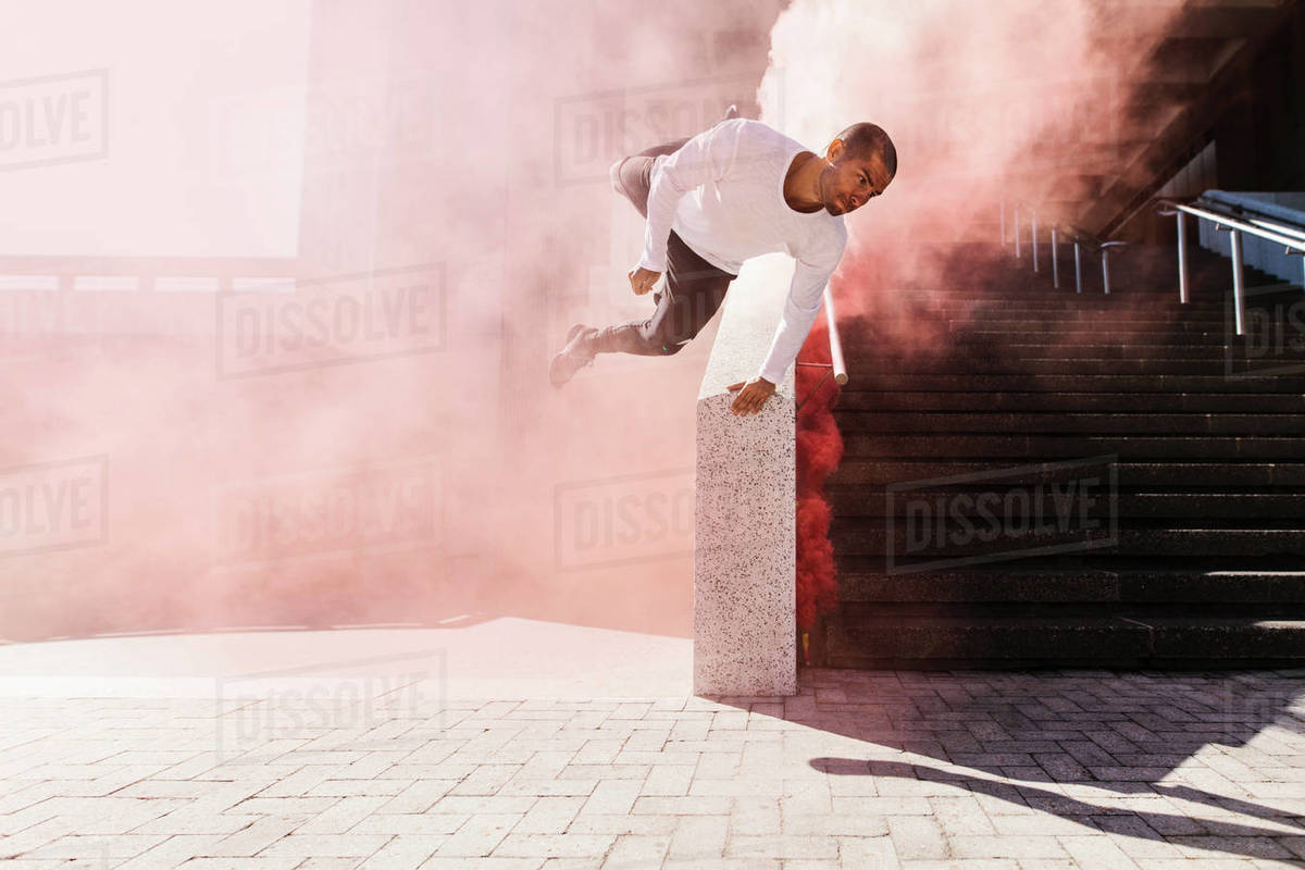 Man practices parkour and free running with smoke grenade. Young male practicing parkour in urban space. Royalty-free stock photo