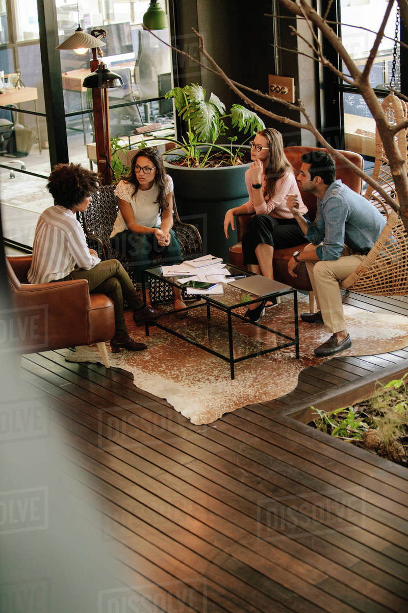 Vertical shot of corporate professionals discussing new ideas in office lobby. Creative business