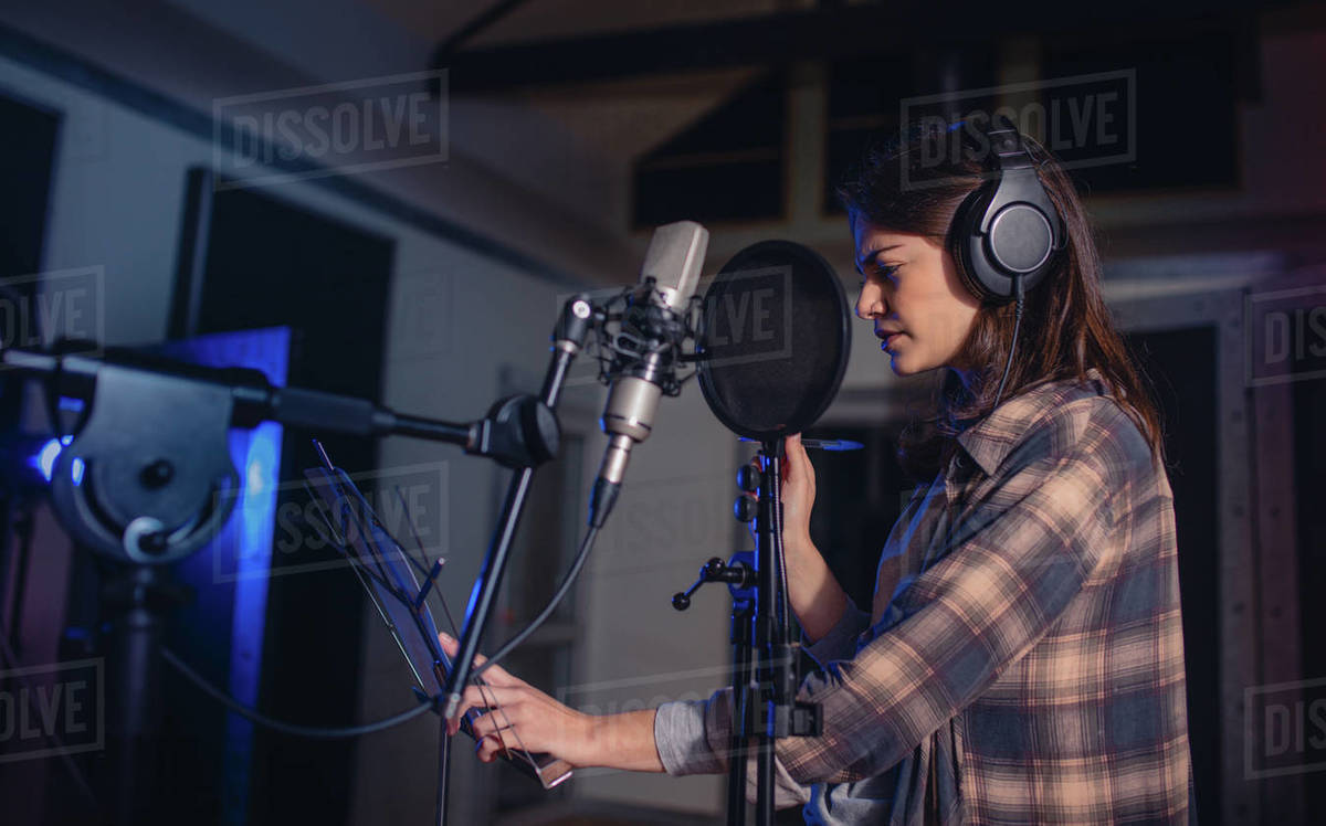 Woman recording music in a professional recording studio. Female singer ...