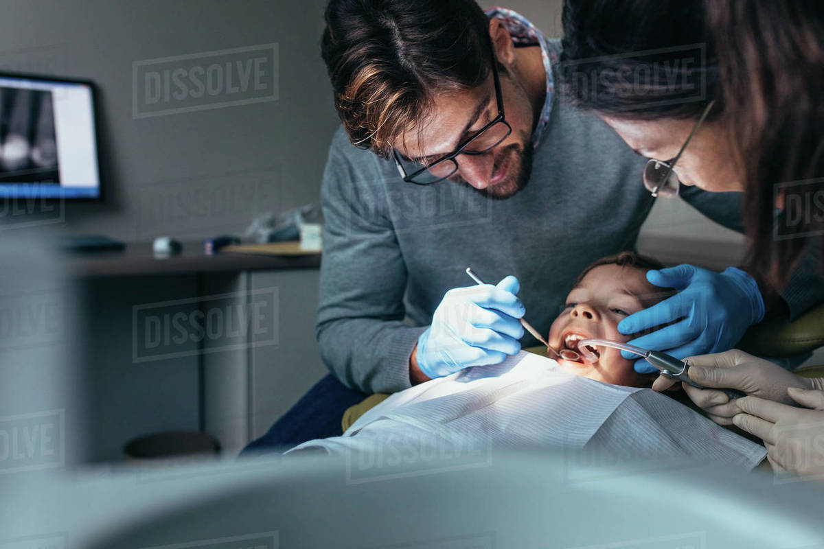 Dentist with female nurse examining a patients teeth at the dental