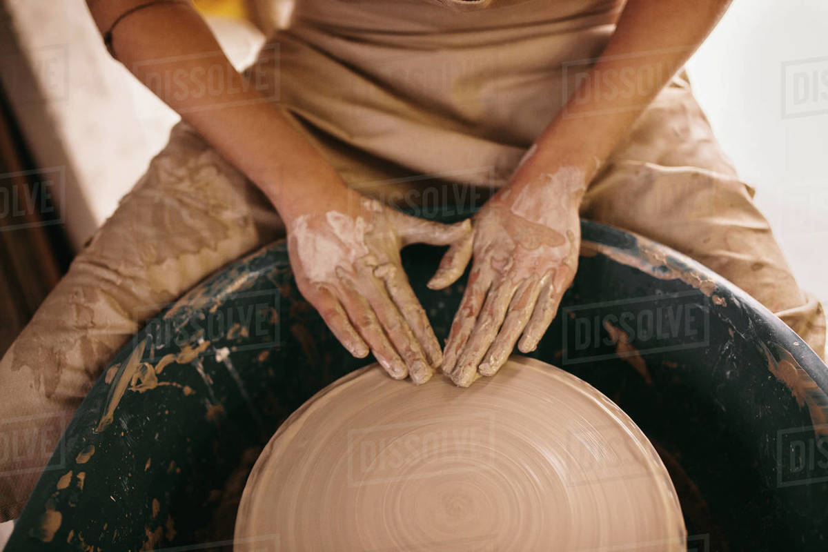 Potter flattening clay on pottery wheel in Craftswoman