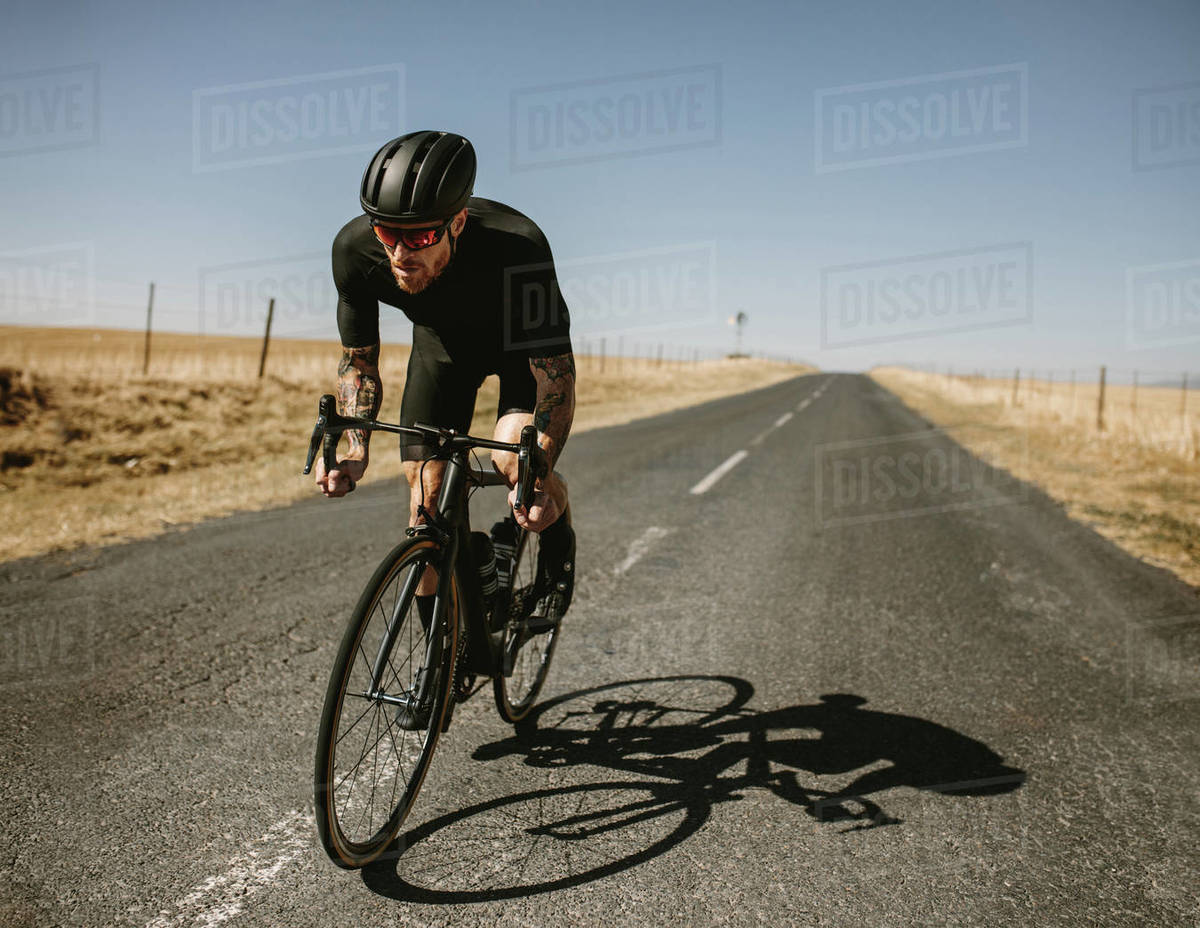 Racer riding a bicycle on the empty road. Male athlete riding a bike on
